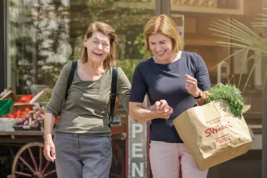 Freiwillige Duo-Partnerin unterstützt ältere Frau beim Einkaufen.