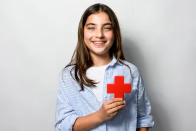 Mädchen hält ein Rotkreuz-Symbol in den Händen