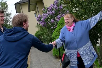 Eine Frau, die Fahrgast ist beim Zürcher Rotkreuz-Fahrdienst, wird von zwei prominenten Spielern des EHC Kloten begrüsst.