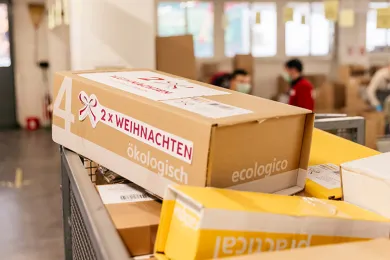 Ein "2 x Weihnachten"-Päckli steht auf einem Päckliwagen. 