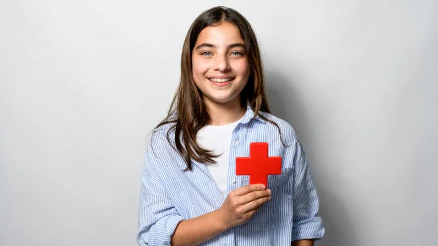 Mädchen hält ein Rotkreuz-Symbol in den Händen