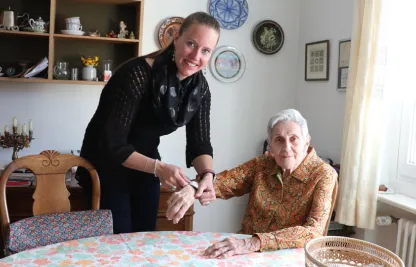 Eine Freiwillige passt das Notruf-Armband bei der Kundin an