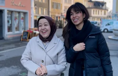 Zwei Frauen, die lachend gemeinsam durch die Stadt laufen 